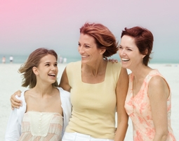 Foto di tre donne che si tengono vicine, una più giovane a sinistra e due più anziane a destra.