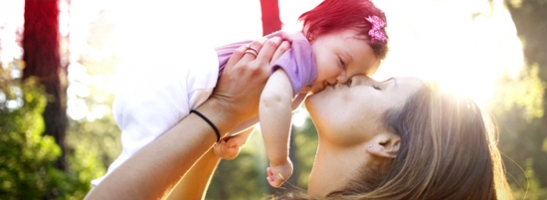 Foto di una donna che solleva e bacia una bambina.